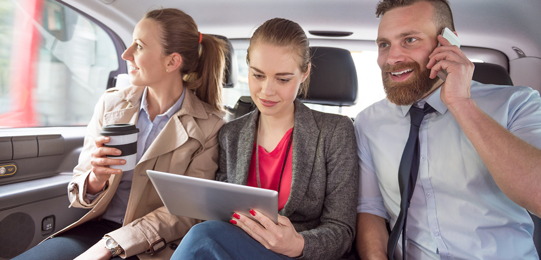 Three business people sitting in the back of a car