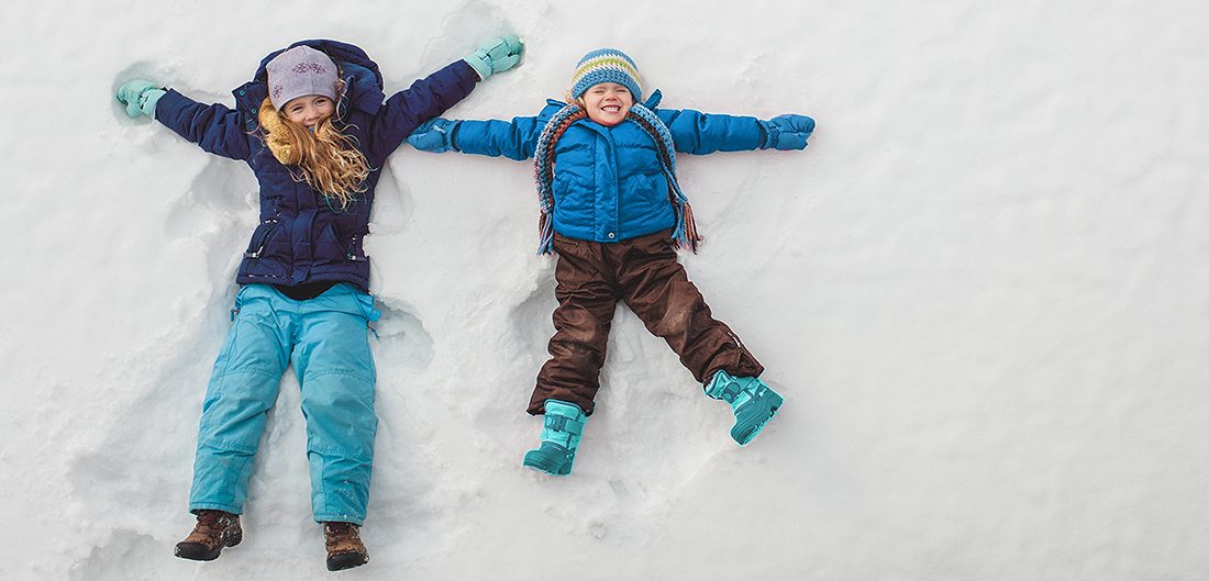 two young children make snow angels
