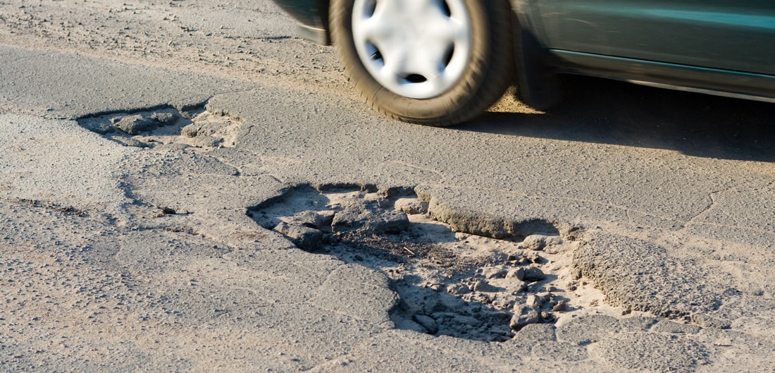 car driving by a pothole